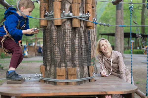 Een kleine jongen is trainen in een touw park. Het kind klimt de hindernisbaan. Actieve recreatie in het Park in de frisse lucht. — Stockfoto