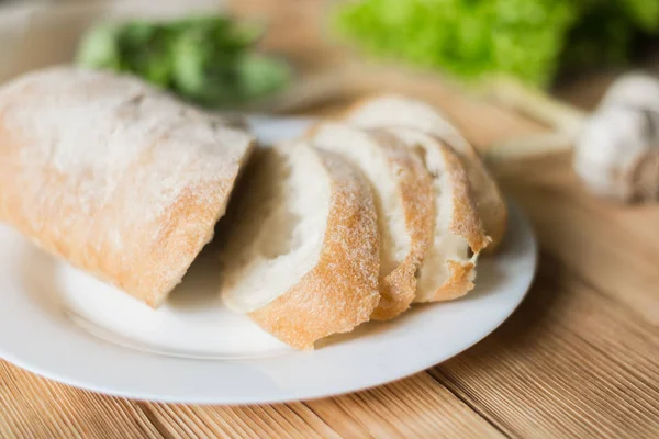 Sliced bread, ciabatta on a white plate. Preparation for the preparation of bruschetta. — Stock Photo, Image