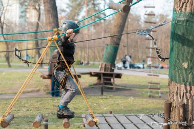 Küçük bir çocuk engelli parkurdan geçiyor. Parkta temiz havada çocuğun aktif fiziksel rekreasyon. Çocuklar için eğitim.