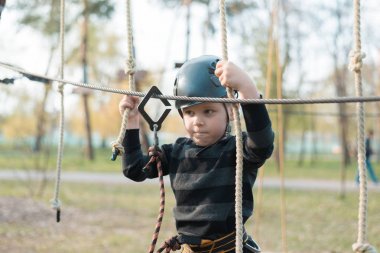 Küçük bir çocuk engelli parkurdan geçiyor. Parkta temiz havada çocuğun aktif fiziksel rekreasyon. Çocuklar için eğitim.
