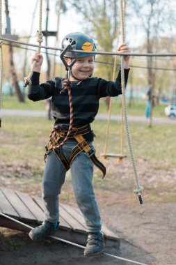 Küçük bir çocuk engelli parkurdan geçiyor. Parkta temiz havada çocuğun aktif fiziksel rekreasyon. Çocuklar için eğitim.