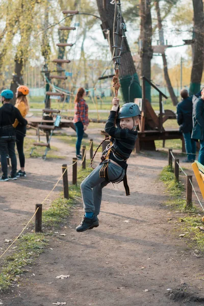 Un ragazzino sta superando un percorso ad ostacoli. Ricreazione fisica attiva del bambino all'aria aperta nel parco. Formazione per bambini . — Foto Stock