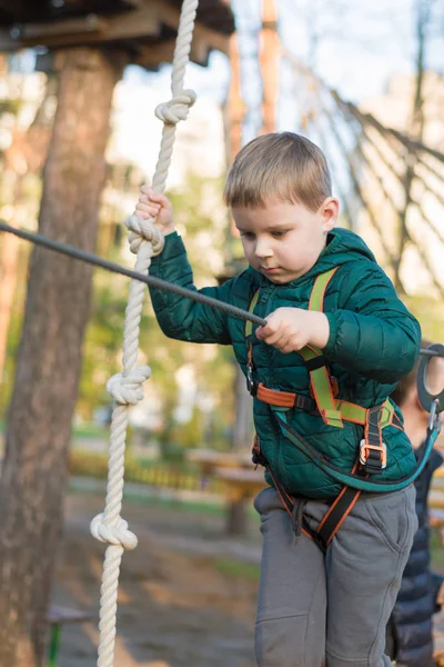 Chlapeček v lanové parku. Aktivní fyzické rekreace dítěte v čerstvém vzduchu v parku. Školení pro děti. — Stock fotografie