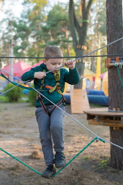 Un niño en un parque de cuerdas. Recreación física activa del niño al aire libre en el parque. Formación para niños . — Foto de Stock