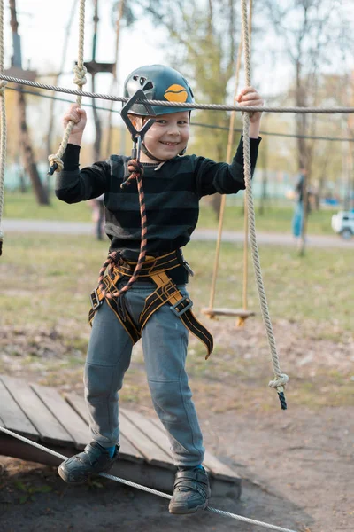 Küçük bir çocuk engelli parkurdan geçiyor. Parkta temiz havada çocuğun aktif fiziksel rekreasyon. Çocuklar için eğitim.