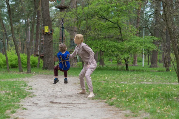 Η μαμά κάνει τον γιο της στο τελεφερίκ. Ψυχαγωγικές δραστηριότητες στο πάρκο. Αμοιβαία αλληλεπίδραση μεταξύ μητέρας και παιδιού. — Φωτογραφία Αρχείου