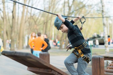 Küçük bir çocuk engelli parkurdan geçiyor. Parkta temiz havada çocuğun aktif fiziksel rekreasyon. Çocuklar için eğitim.