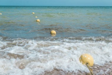 Sahile yakın denizde sarı eskrim şamandıralar. Yüzme için güvenlik önlemleri.
