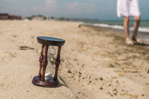 Reloj de arena en la arena. El concepto de tiempo . —  Fotos de Stock