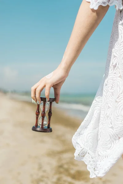 Timglas i kvinnlig hand på stranden. Tid till vila, Relax koncept. — Stockfoto