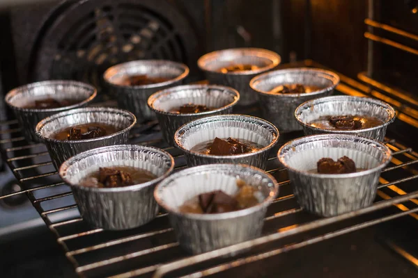 Surowe babeczki w formach w piekarniku. Gotowanie babeczki czekoladowe. — Zdjęcie stockowe