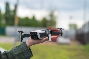 Gökyüzüne karşı bir kadın elinde uçan drone.