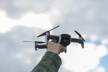 Gökyüzüne karşı bir kadın elinde uçan drone.