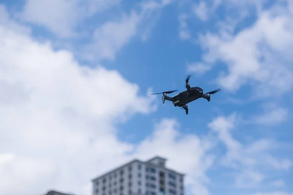 Flying drone against the sky with clouds and buildings. — Stock Photo, Image