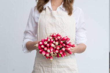 Hafif bir arka plan üzerinde kadın elinde doğal turp bir demet. Sağlıklı beslenme kavramı, vejetaryenlik.