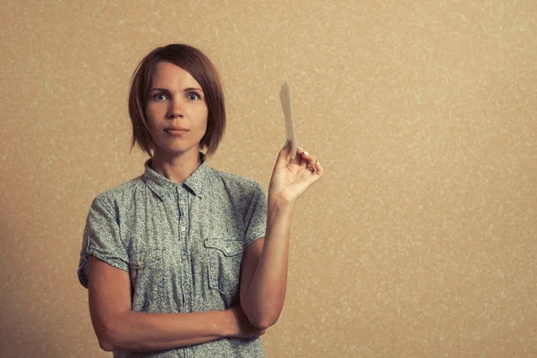 A middle aged woman holds a sanitary pad and looks into the camera on a uniform background. Place for copy space. — Stock Photo, Image