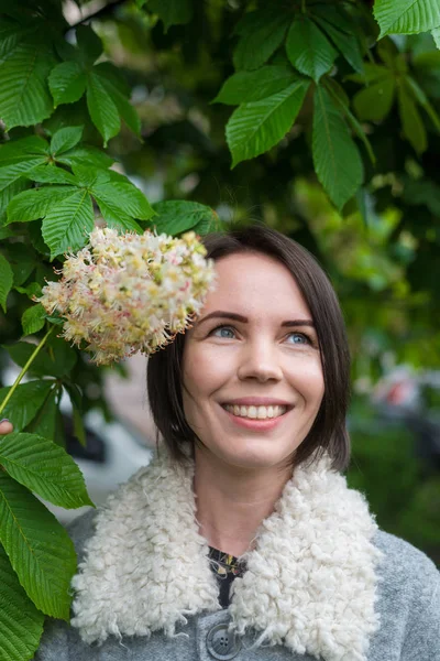 Een middelbare leeftijd brunette vrouw is schattig glimlachend in de buurt van een bloeiende boom. — Stockfoto