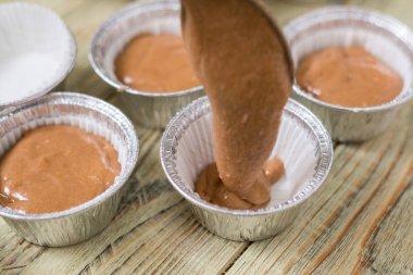 Ahşap arka plan üzerinde pişirme yemekleri çiğ muffin hamur. Pişirme çikolatalı kekler.