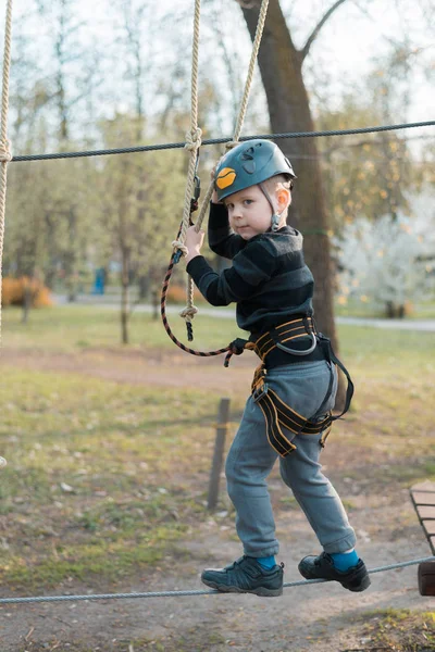 Um rapazinho está a passar um curso de obstáculos. Recreação física ativa da criança ao ar livre no parque. Treinamento para crianças . — Fotografia de Stock