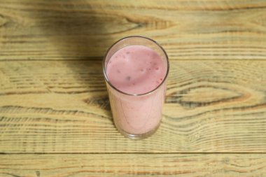 Ahşap bir arka plan üzerinde bir bardak meyve pembe yoğurt.