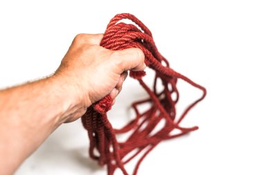 Erkek el beyaz arka plan üzerinde izole shibari için ip tutar.