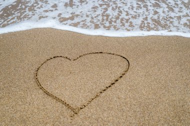 Sahilde kuma çekilen kalp, okyanus.