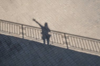 Köprüden el sallayan bir adamın gölgesi.