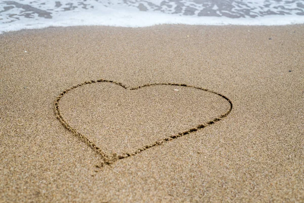 Heart drawn in the sand on the beach, ocean.