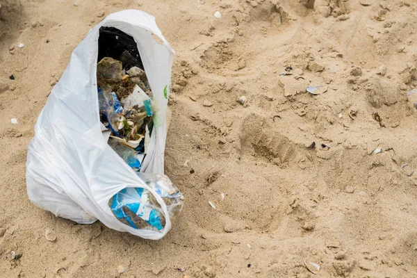 A package of garbage collected on the sand by the sea. The concept of environmental protection. — Stock Photo, Image