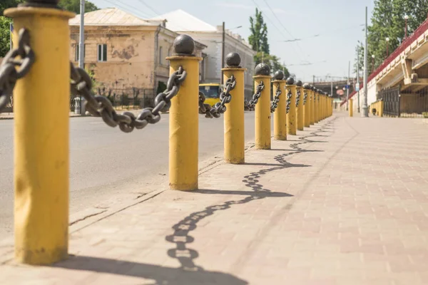 Esgrima cadeia grossa em pilares amarelos ao longo da estrada . — Fotografia de Stock
