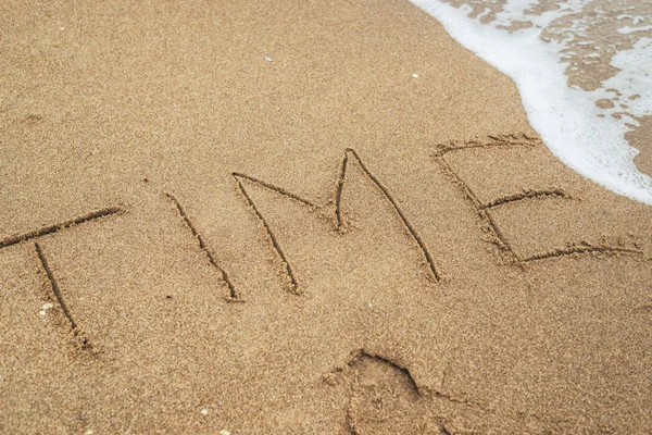 Il tempo è il concetto ultimo. La parola Tempo scritto nella sabbia e scomparire sotto l'influenza dell'onda del mare . Foto Stock