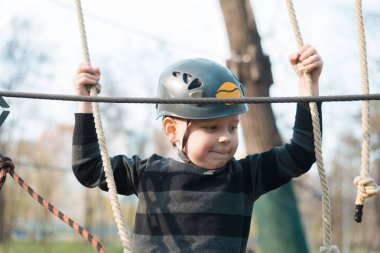 Küçük bir çocuk engelli parkurdan geçiyor. Parkta temiz havada çocuğun aktif fiziksel rekreasyon. Çocuklar için eğitim.