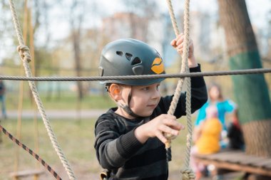 Küçük bir çocuk engelli parkurdan geçiyor. Parkta temiz havada çocuğun aktif fiziksel rekreasyon. Çocuklar için eğitim.