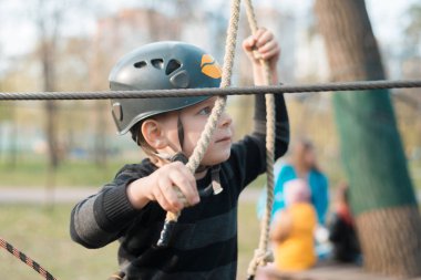 Küçük bir çocuk engelli parkurdan geçiyor. Parkta temiz havada çocuğun aktif fiziksel rekreasyon. Çocuklar için eğitim.