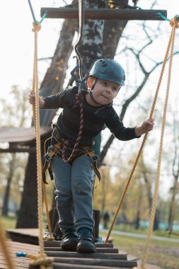 Küçük bir çocuk engelli parkurdan geçiyor. Parkta temiz havada çocuğun aktif fiziksel rekreasyon. Çocuklar için eğitim.