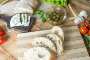 Bruschetta pişirme için Malzemeler: doğranmış ciabatta, zeytin, domates, ahşap bir arka plan üzerinde mavi peynir. Sağlıklı ve lezzetli yemekler pişirme.