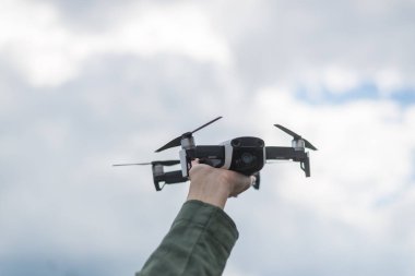 Gökyüzüne karşı bir kadın elinde uçan drone.