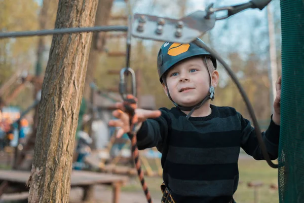 Een kleine jongen passeert een hindernisbaan. Actieve fysieke recreatie van het kind in de frisse lucht in het Park. Training voor kinderen. — Stockfoto