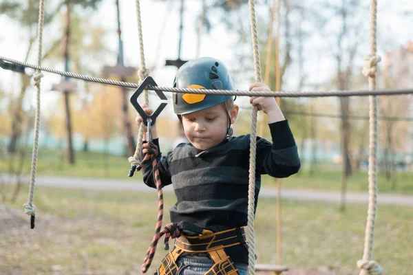 Een kleine jongen passeert een hindernisbaan. Actieve fysieke recreatie van het kind in de frisse lucht in het Park. Training voor kinderen. — Stockfoto