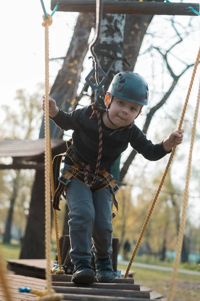 Een kleine jongen passeert een hindernisbaan. Actieve fysieke recreatie van het kind in de frisse lucht in het Park. Training voor kinderen. — Stockfoto