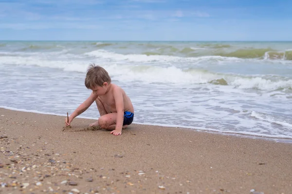 Маленький мальчик играет у воды у моря . — стоковое фото