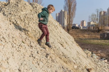 Küçük bir çocuk kum dağına tırmanıyor..
