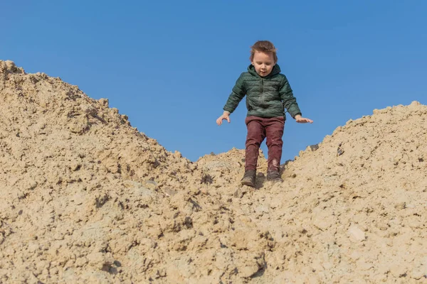 Маленький мальчик взбирается на песчаную гору . — стоковое фото