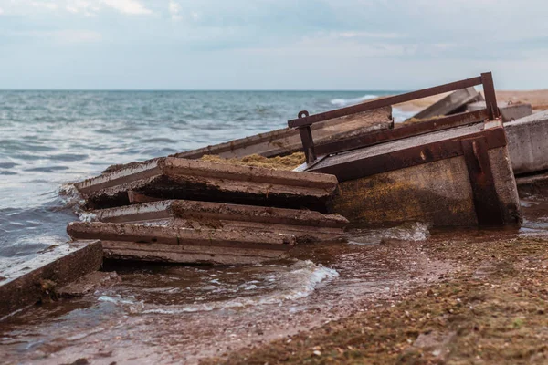 Destruction de la tempête en mer. Blocs de béton brisé d'un bâtiment dans les vagues . — Photo