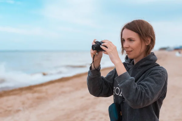 Žena průměrných let dělá fotku na pobřeží, oceán. — Stock fotografie