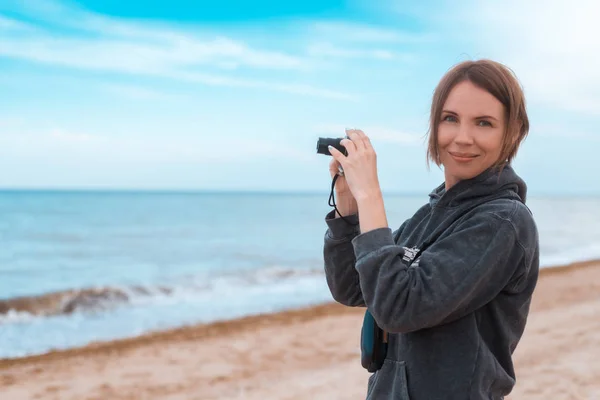 Žena průměrných let dělá fotku na pobřeží, oceán. — Stock fotografie