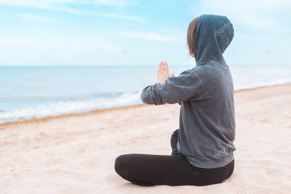 Woman practicing meditation on the seashore, ocean. Practice clearing thoughts, calming down. Yoga on the coast.