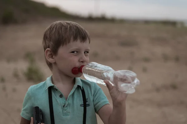 Un niño bebe agua de una botella. . — Foto de Stock