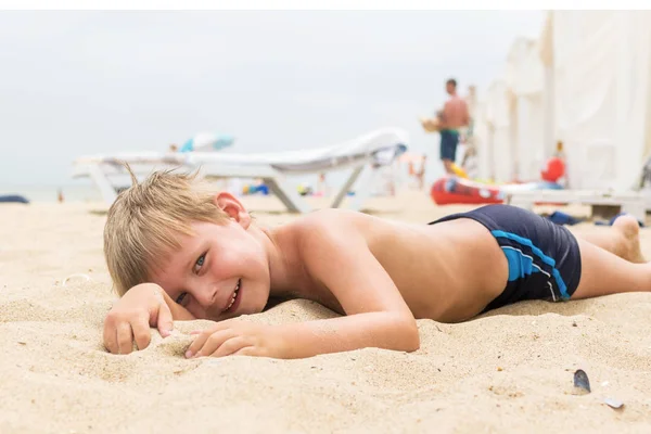 Malý chlapec leží v létě na písku. Zbytek dítěte na pláži. — Stock fotografie
