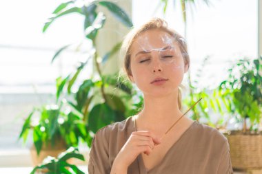 Genç güzel bir kız elinde sigara aromatik sap tutar. Aromaterapi, meditasyon, sağlıklı yaşam kavramı.